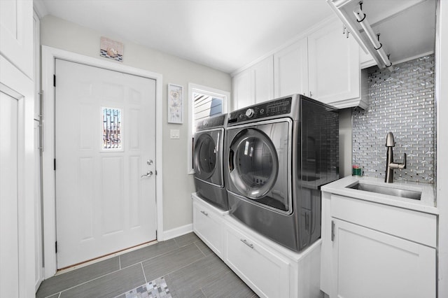 laundry area featuring washer and dryer, baseboards, cabinet space, and a sink
