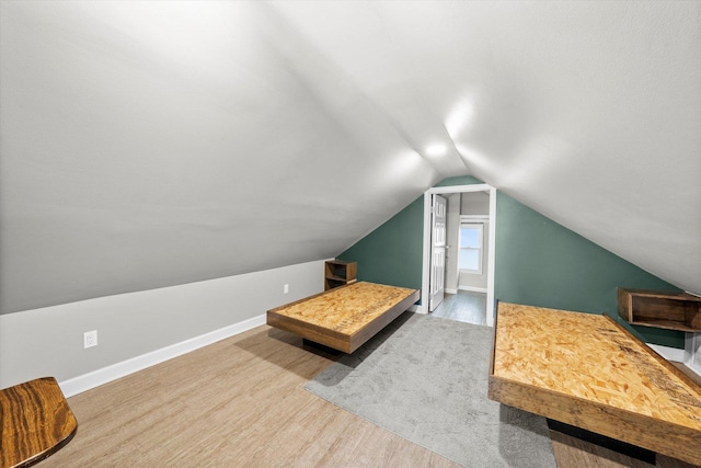 unfurnished bedroom with baseboards, lofted ceiling, and wood finished floors
