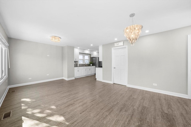 unfurnished living room featuring baseboards, wood finished floors, and visible vents