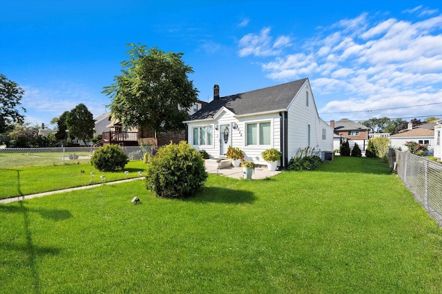 back of house featuring a lawn, a chimney, a fenced backyard, a patio, and entry steps