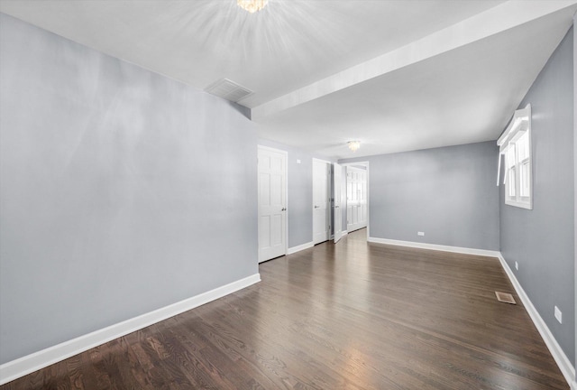 empty room featuring baseboards, visible vents, and dark wood-style flooring