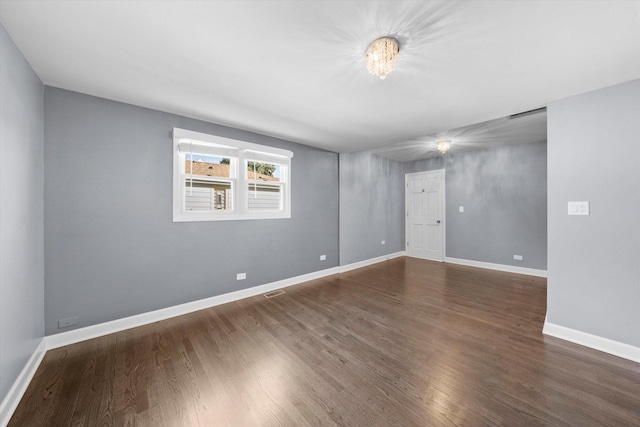spare room featuring wood finished floors, visible vents, and baseboards