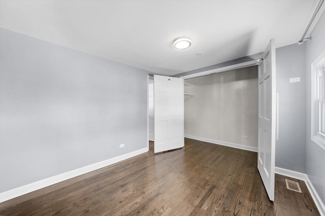 unfurnished bedroom featuring a closet, dark wood finished floors, visible vents, and baseboards