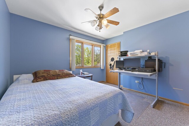 carpeted bedroom featuring an office area, ceiling fan, and baseboards