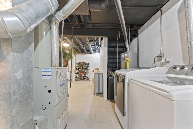 laundry room featuring water heater, washing machine and dryer, and light tile patterned floors