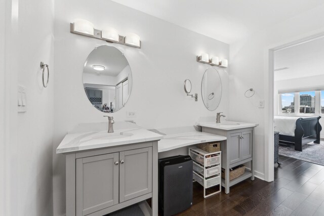 bathroom with a sink, double vanity, wood finished floors, and connected bathroom