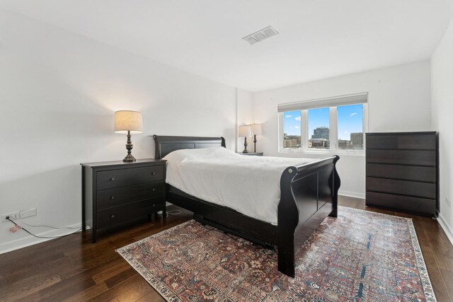 bedroom with baseboards, dark wood-type flooring, and visible vents