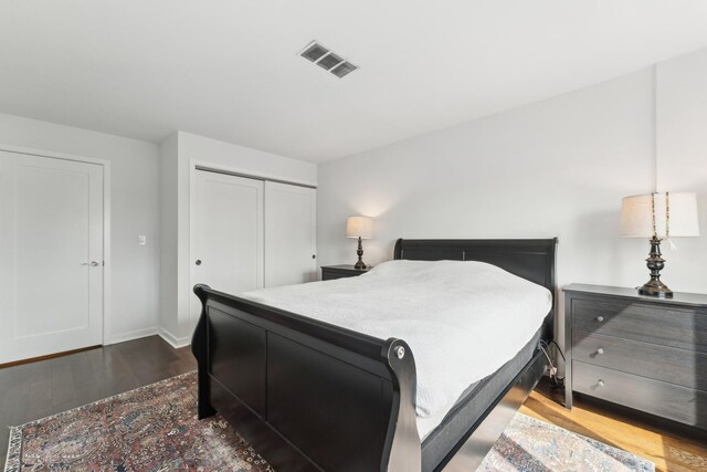 bedroom with visible vents, baseboards, wood finished floors, and a closet