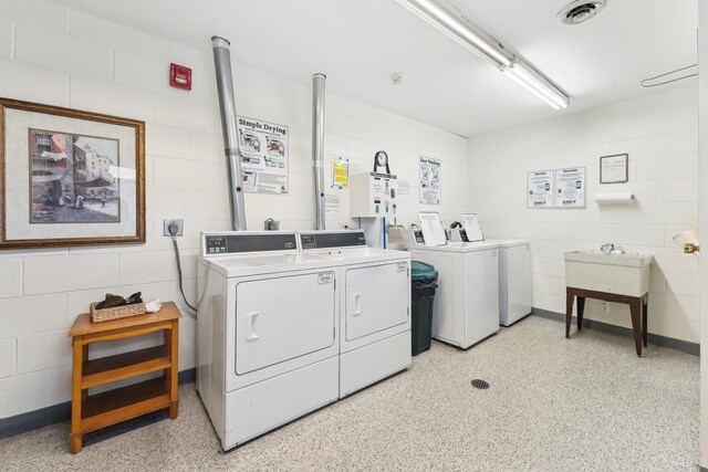 shared laundry area featuring concrete block wall, visible vents, and washing machine and clothes dryer