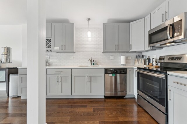 kitchen featuring light countertops, appliances with stainless steel finishes, a sink, and tasteful backsplash