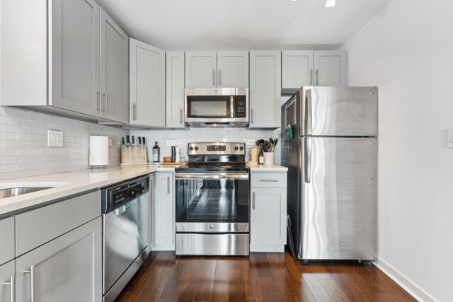kitchen featuring light countertops, gray cabinets, decorative backsplash, and stainless steel appliances