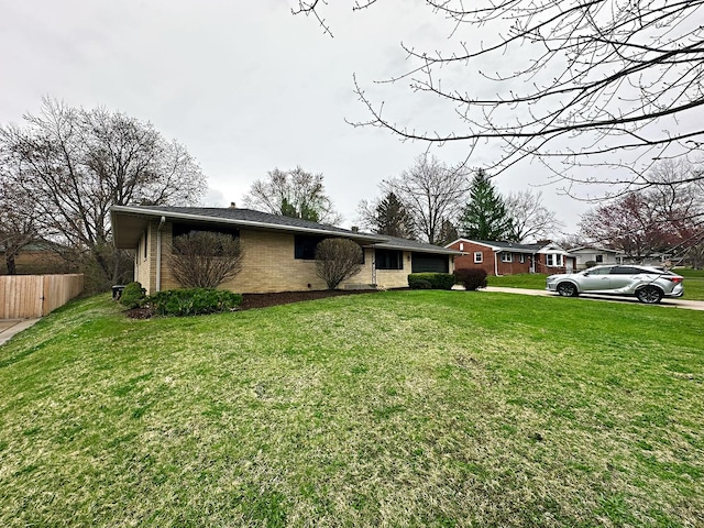 exterior space with a front lawn, driveway, fence, brick siding, and a garage
