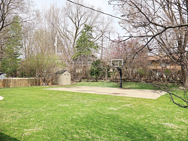 view of yard featuring fence, basketball court, an outdoor structure, and a shed