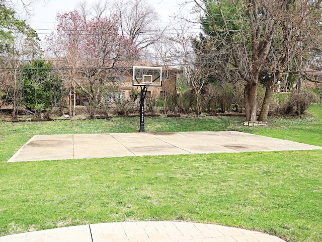 view of basketball court featuring basketball hoop and a yard