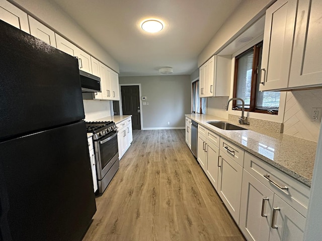 kitchen with white cabinets, stainless steel appliances, a sink, and light wood-type flooring