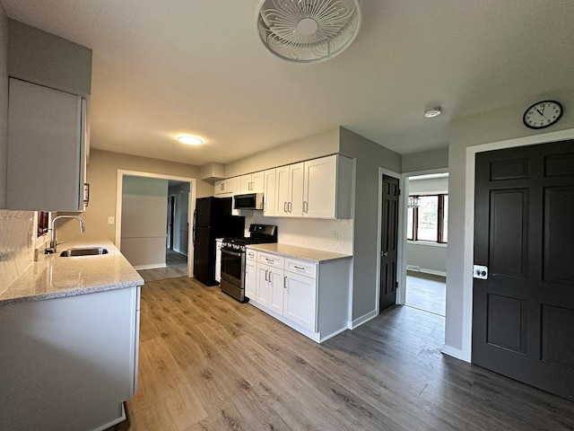 kitchen featuring a sink, baseboards, light wood-style floors, white cabinetry, and appliances with stainless steel finishes