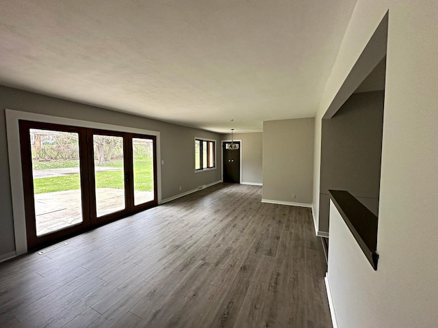 unfurnished living room featuring baseboards, visible vents, and dark wood-style floors