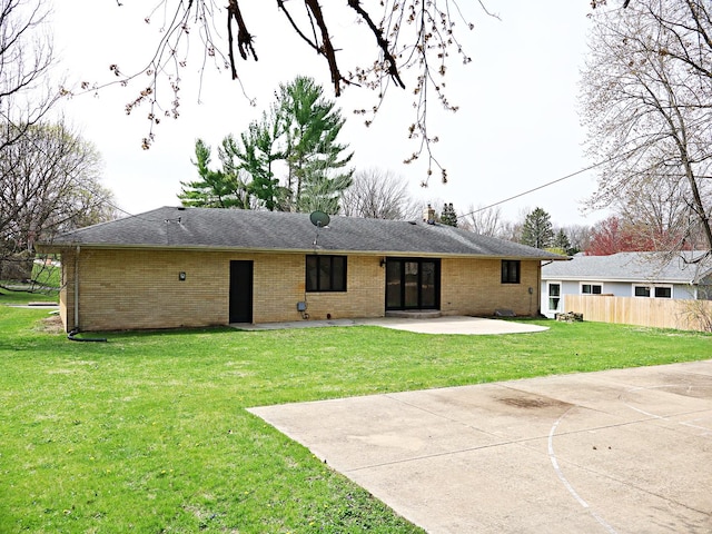 rear view of house with brick siding, a patio area, a lawn, and fence
