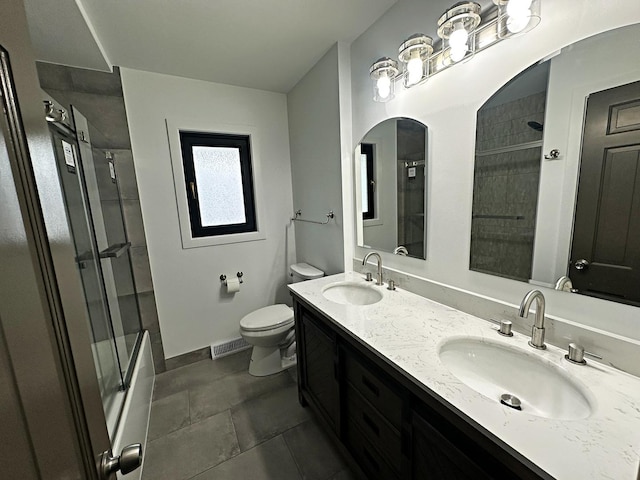 bathroom featuring double vanity, visible vents, toilet, and a sink