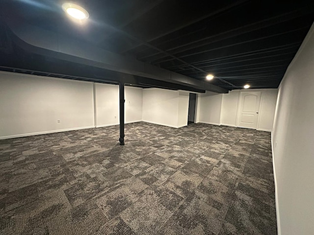 finished basement featuring dark colored carpet and baseboards