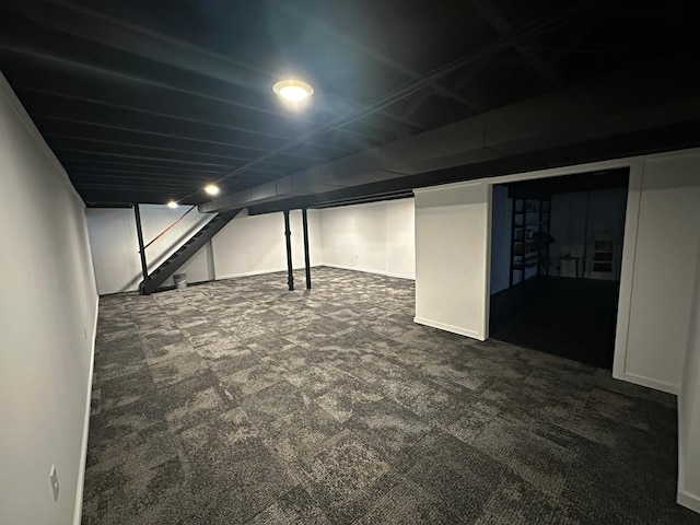 finished below grade area with dark carpet, stairway, and baseboards