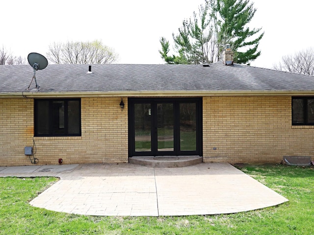 rear view of house with brick siding, roof with shingles, and a patio
