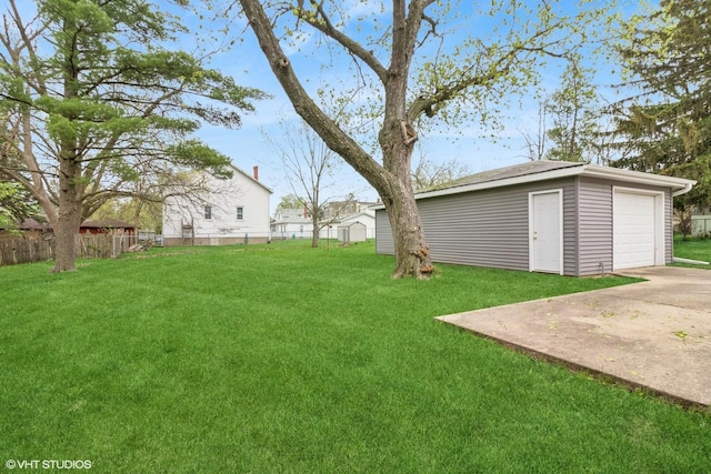 view of yard featuring driveway, an outbuilding, and a detached garage
