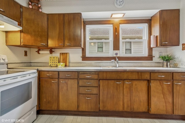 kitchen with electric stove, a sink, ventilation hood, light countertops, and brown cabinetry