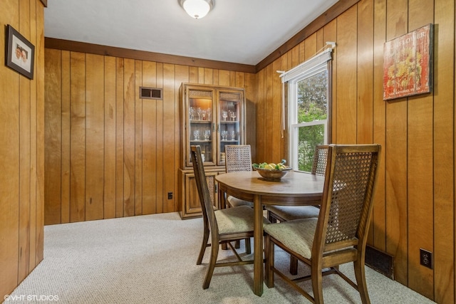 carpeted dining room with wood walls
