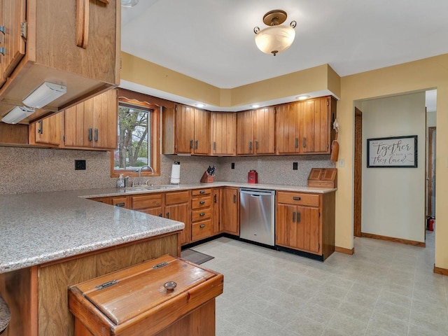 kitchen with light countertops, dishwasher, brown cabinetry, and a sink