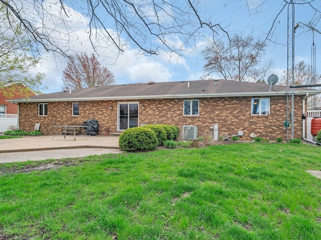 rear view of property featuring fence, brick siding, a yard, and a patio