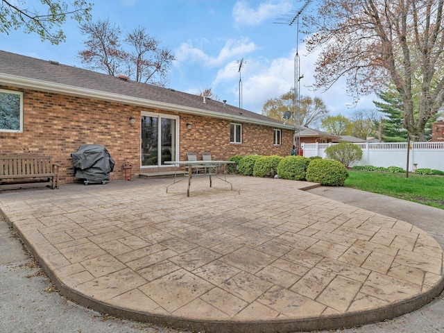 rear view of property featuring brick siding, fence, and a patio area