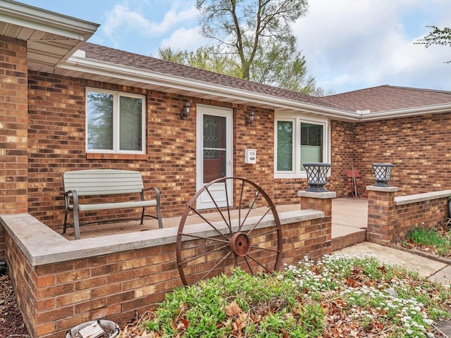 view of front of home with brick siding and roof with shingles