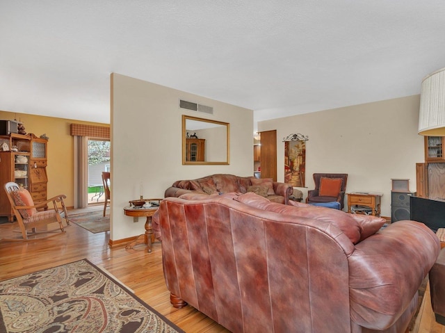 living area with baseboards, visible vents, and light wood-style flooring