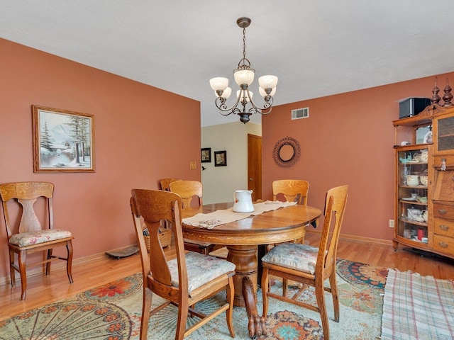 dining room featuring light wood-style floors, visible vents, baseboards, and an inviting chandelier