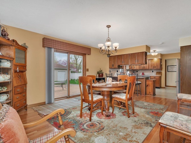 dining space featuring light wood finished floors, baseboards, and a notable chandelier