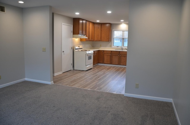 kitchen with visible vents, baseboards, white range with gas stovetop, and light colored carpet