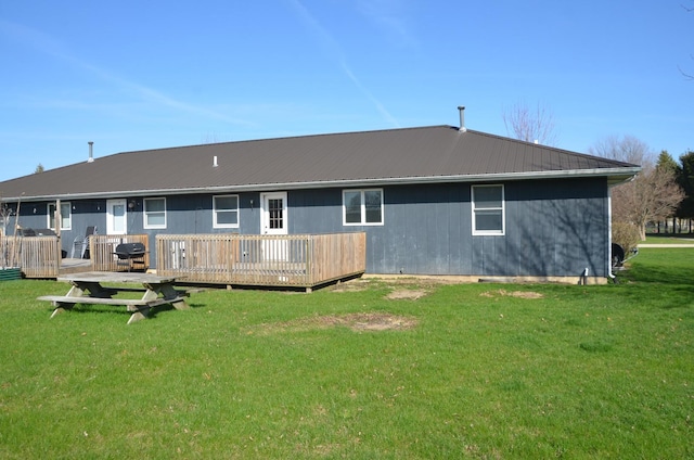 back of house with metal roof, a deck, and a lawn