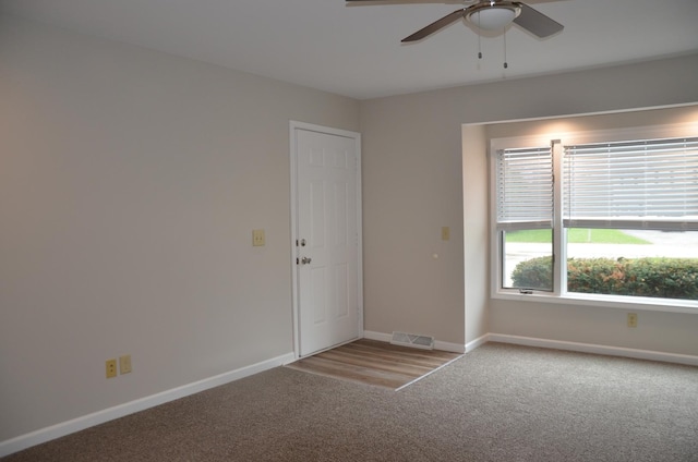 spare room with carpet floors, ceiling fan, visible vents, and baseboards