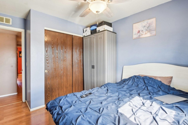 bedroom featuring baseboards, visible vents, a ceiling fan, wood finished floors, and a closet