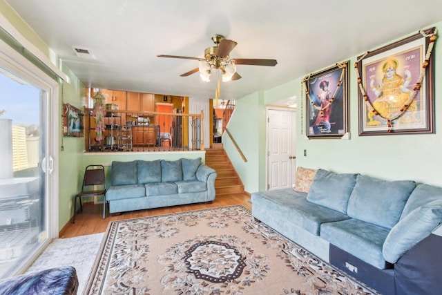 living area with stairway, ceiling fan, wood finished floors, and visible vents