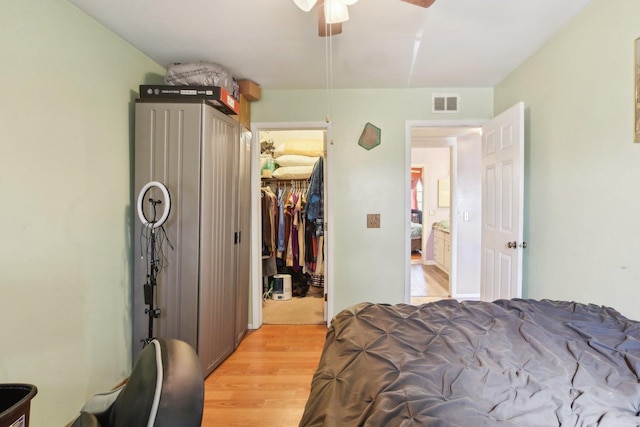 bedroom with visible vents, a walk in closet, light wood-style floors, a closet, and ceiling fan