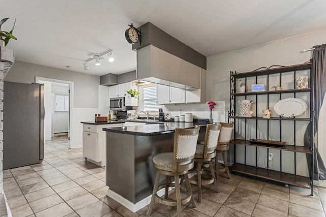 1003 Poplar St, Monticello, IL 61856 - kitchen with appliances with stainless steel finishes, dark countertops, white cabinetry, a peninsula, and a center island