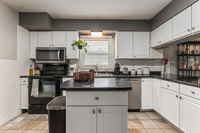 1003 Poplar St, Monticello, IL 61856 - kitchen featuring appliances with stainless steel finishes, a sink, white cabinets, a center island, and light tile patterned flooring
