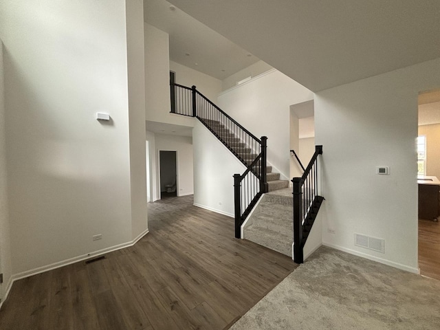 staircase with wood finished floors, visible vents, and baseboards