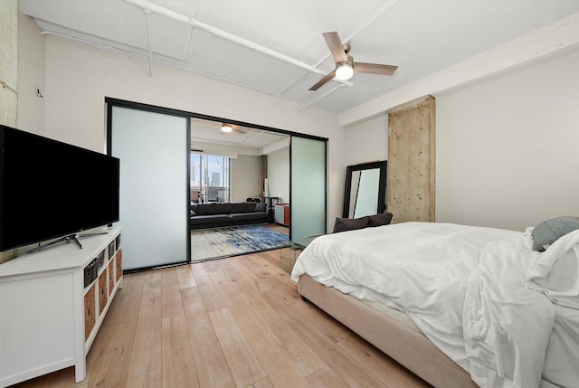 bedroom featuring attic access, light wood finished floors, and a ceiling fan