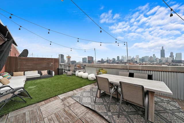 view of patio featuring a fenced backyard, a wooden deck, a city view, and outdoor dining area
