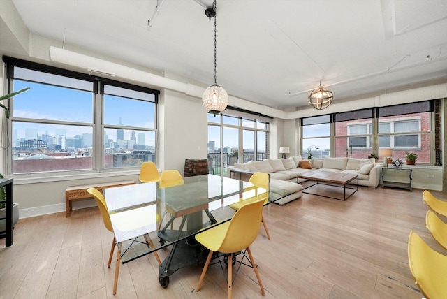 dining room with a city view, light wood-style floors, and baseboards