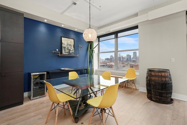 dining room featuring a city view, light wood-style flooring, baseboards, and beverage cooler