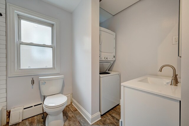 4158 W Nelson St, Chicago, IL 60641 - bathroom featuring stacked washer / drying machine, wood finished floors, toilet, a baseboard heating unit, and baseboards